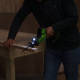 Person using a cordless drill on a wooden surface with a workshop setting.